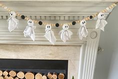 a fireplace decorated for halloween with white and black paper ghost decorations on the mantel