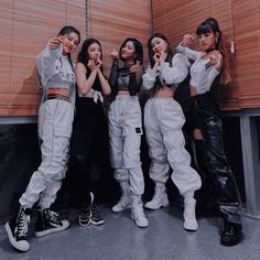 four girls standing in front of a wall with their hands on their hipss and posing for the camera