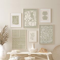 a white table topped with lots of pictures and vases on top of it next to a wall