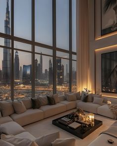 a living room filled with lots of furniture and large windows overlooking the cityscape