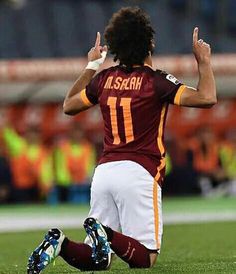 a soccer player kneeling on the ground with his hands in the air