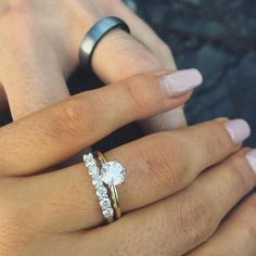 a woman's hand with two rings on her fingers and one ring in the middle