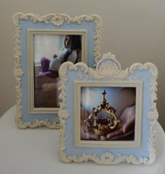 two framed pictures sitting on top of a white toilet next to each other, one holding a cross and the other holding a crown