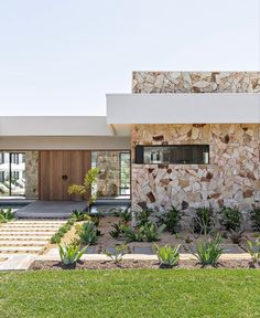 a modern house with stone walls and green grass