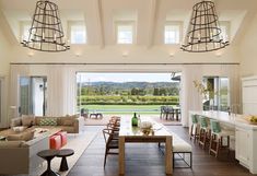 a living room filled with furniture next to a kitchen and dining room table in front of a large window