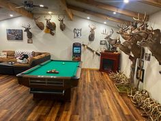 a living room filled with lots of furniture and deer heads on the wall above a pool table