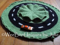 a crocheted hat is sitting on top of a wooden floor with a candy bar in the middle