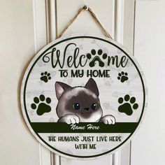 a welcome sign hanging on the front door with a cat's face and paw prints