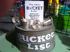 an old bucket with some cups on it and a sign that says bucket list next to it