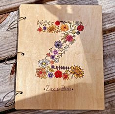 a personalized wooden notebook with flowers and the number seven engraved on it's cover