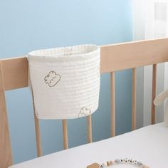 a baby crib with a teddy bear hanging from it's side next to a toy