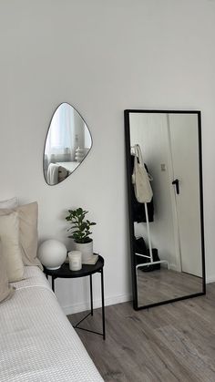 a bedroom with a bed, mirror and plant on the side table in front of it