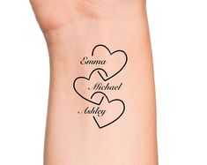 two hearts tattoo on the wrist that says, comma michael and askley in cursive writing