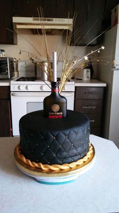 a cake with a bottle on top of it sitting on a table in front of a stove