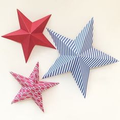 three red, white and blue paper stars on a white surface with one folded in the shape of an origami star