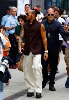 a man with dreadlocks walking down the street in front of a group of people