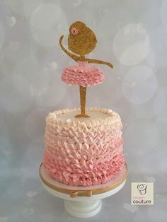 a cake decorated with pink and gold icing on top of a white pedestal in the shape of a ballerina