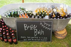 a metal tub filled with bottles of beer next to a sign that says booze buh