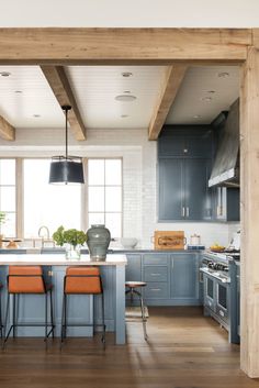 an open kitchen with blue cabinets and wooden beams on the ceiling, along with orange chairs