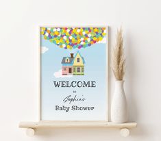 a baby shower sign with a hot air balloon in the sky and a house on it