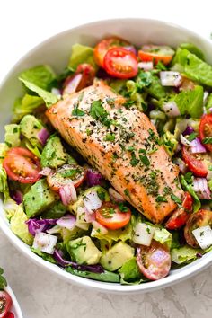 a white bowl filled with salad and salmon