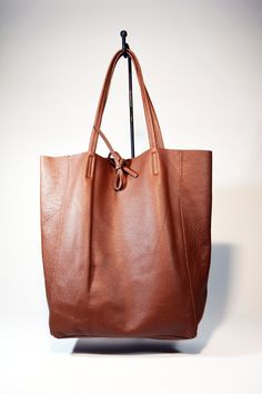 A lightweight and spacious Leather Shopper Bag-Tan you can use for your office, gym and after-hours essentials while still looking stylish. Handmade from supple calfskin Italian leather, the versatile look features over-the-shoulder handles and minimal detailing. Raw edges and no lining makes this style super light and easy to fold when traveling. Inside is a zippered document pouch and a leather cell phone pouch. Details: Color: TanTwo leather strap for closing the bag.Natural unlined interiorM Brown Leather Tote Bag, Leather Shopper Bag, Office Gym, Cell Phone Pouch, Brown Leather Bag, Phone Pouch, Black Leather Bags, Shopper Bag, Black Bag