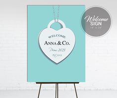 a welcome sign with a heart hanging from it's side on a easel