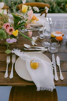 an outdoor table set with flowers and silverware