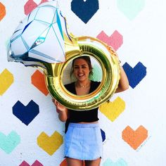 a woman holding up a balloon and a mirror