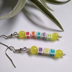 The perfect sunny earrings to accessorize your bathing suit, or to subtly let everyone know where you would rather be.  White beads with multicolored letters, yellow glass beads and tiny white glass beads.  Rubber backings included for secure wearing. Earrings Summer, Summer Earrings, Summer Earring, Letter Beads, Beach Bum, Bead Earrings, White Beads, White Glass, Bathing Suit