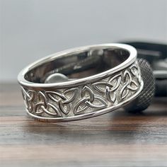 two wedding rings sitting on top of a wooden table next to a camera and cell phone