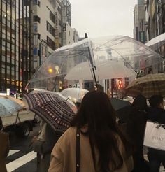 people walking in the rain with umbrellas on a city street near buildings and cars