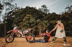 a man laying on the ground next to a woman in front of a dirt bike