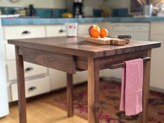 a wooden table with two oranges on it and a towel hanging from the end