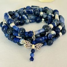 This unique jewelry piece is made with a variety of sodalite beads accented with silver tone beads and a silver tone dragonfly charm. It's made on durable stretch cord that measures approx. 36" at the longest so it can be worn as a wrap bracelet or a necklace! Adjustable Sodalite Gemstone Beaded Bracelets, Hand-strung Blue Sodalite Bracelet, Blue Hand-strung Sodalite Bracelet, Blue Sodalite Hand-strung Bracelet, Adjustable Sodalite Beaded Bracelets, Sodalite Beaded Bracelets With Natural Stones For Gift, Blue Sodalite Hand-strung Beaded Bracelets, Silver Beaded Bracelet With Lapis Lazuli And Natural Stones, Spiritual Sodalite Gemstone Beaded Bracelets