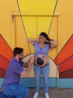 a man kneeling down next to a woman holding a ball