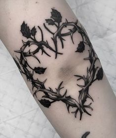 a black and white photo of a leafy branch tattoo on the right arm with leaves around it