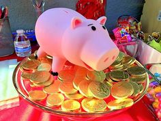 a pink pig sitting on top of a pile of gold coins