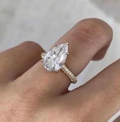 a woman's hand with a diamond ring on top of her finger and an engagement band