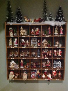 a wooden shelf filled with lots of christmas figurines on top of snow covered shelves