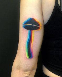 a colorful mushroom tattoo on the left arm and shoulder, with a rainbow stripe across it