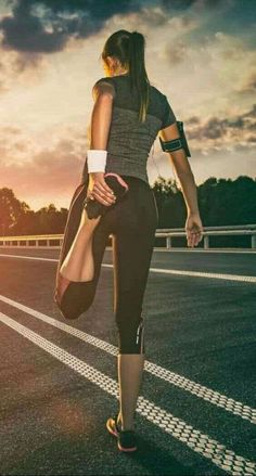 a woman is running on the road at sunset