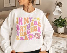 Celebrate the precious moments of teaching with our "In My Daycare Teacher Era Sweatshirt." Whether you're in the classroom or enjoying some well-deserved downtime, you'll feel at ease.  ♡T-SHIRT * Relaxed fit * 100% Soft cotton * Light fabric for comfort ♡SWEATSHIRT  * Loose fit * 50% Cotton; 50% Polyester * Runs true to size, please check size chart for your perfect fit! Wash: For best results wash inside out on cold and line dry. SHIPPING DETAILS ♡ I will always do my best to ship all items a Vacation Shirts, Cotton Lights, Teacher Shirts, Houston Tx, Cool Shirts, Volleyball, Sweat Shirt, Houston, Custom Print