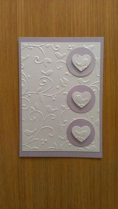 two hearts on a white card in front of a wooden door with the word love