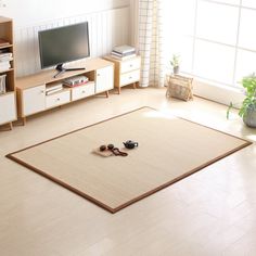 a flat screen tv sitting on top of a wooden stand in a living room next to a window