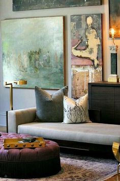 a living room filled with furniture and paintings on the wall above it's couch