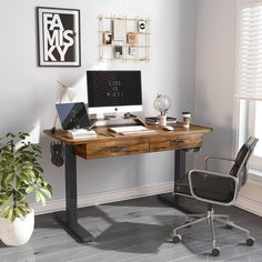 a desk with a computer on it and a chair next to it in front of a window