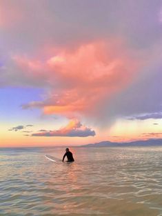 a man riding a surfboard on top of a body of water under a cloudy sky