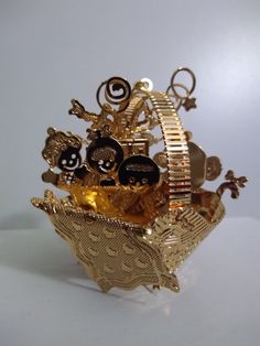 a gold and black brooch with skulls on it's sides, sitting in a basket