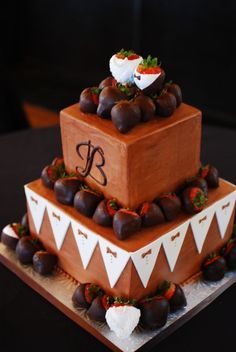 a three tiered cake with strawberries and chocolate on the top, decorated with white bunting